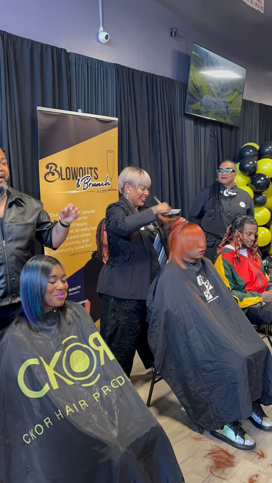Live hairstyling demonstration in front of the Blowouts & Brunch banner